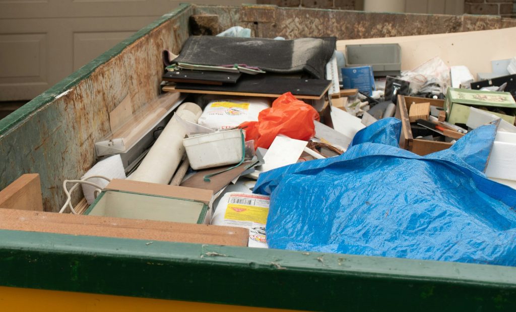 Skip bin full of household waste rubbish on the front yard. House clean up