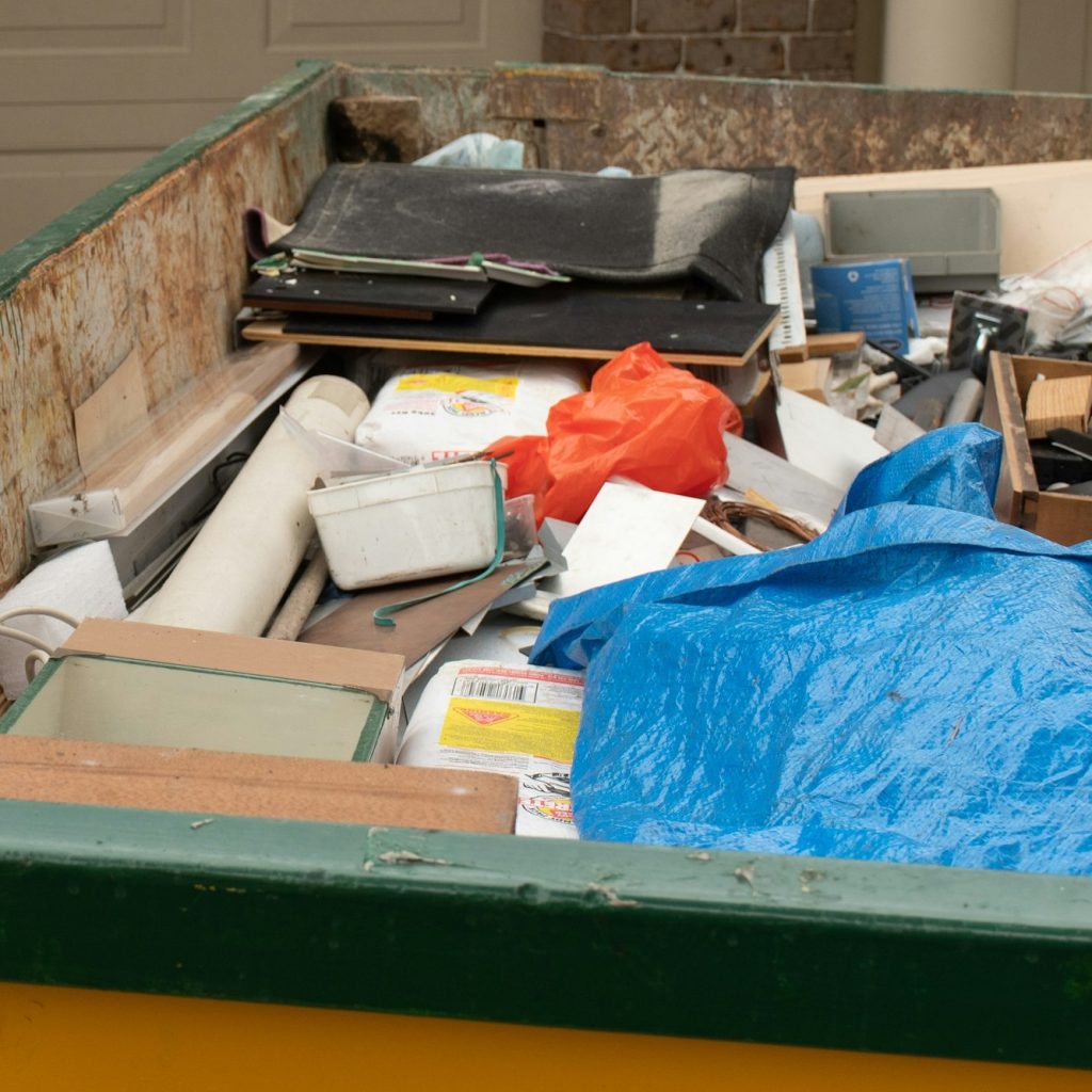 Skip bin full of household waste rubbish on the front yard. House clean up